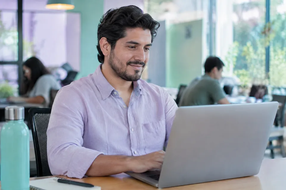 Profesional actualiza su CV en una laptop en un espacio de trabajo.